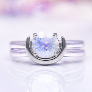 A sterling silver ring with a crescent moon design featuring a moonstone, presented against a white background.