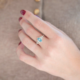 Sterling silver marquise-cut Swiss blue topaz engagement ring with leaf motif displayed in hand against a warm brown backdrop
