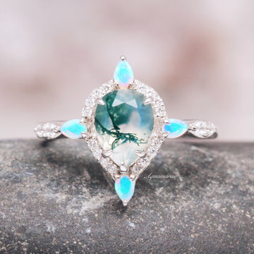 Green Moss Agate & Fire Opal Engagement Ring- 14K White Gold featuring a pear-shaped green moss agate center stone surrounded by sparkling white diamonds and accented with glowing fire opal marquise shapes, designed by Aquamarise Gold.