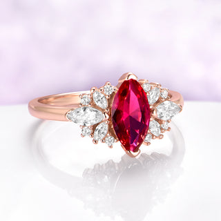 Rose gold ring with a red gemstone and diamond accents on a light purple background
