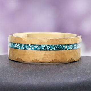 Aquamarine Men's Wedding Band in Gold Tungsten (8mm) by Aquamarise, resting on a grey stone to show the hammered finish and aquamarine inlay.