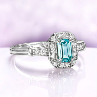 Vintage Halo Aquamarine Ring in Sterling Silver by Aquamarise, featuring a natural emerald-cut blue aquamarine center with a milgrain-edged halo and pavé-set shoulders in a vintage style.