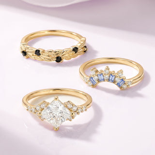 Three gold rings with gemstones on a light pink background