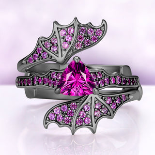 Pink sapphire engagement ring set in black ruthenium — trillion lab-grown hot pink sapphire with pavé bat wings on the wrap band by Aquamarise