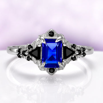 Blue Sapphire & Black Onyx Leaf Engagement Ring- 14K White Gold by Aquamarise Gold, featuring an emerald-cut blue sapphire center with black onyx accents in a nature-inspired leaf design.
