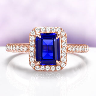 Emerald Cut Sapphire Ring in 14K Rose Gold Vermeil by Aquamarise, featuring a vibrant blue sapphire surrounded by a halo of sparkling diamonds on a rose gold band.