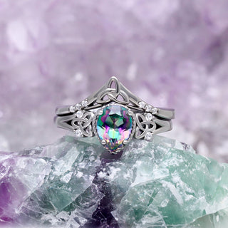 Celtic Knot Mystic Topaz Ring Set in Black by Aquamarise, styled on green and purple crystals to show the Celtic knot bands.