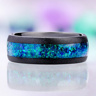 Front view of the sandblasted black tungsten band showing the wide peacock opal inlay between two matte black rails