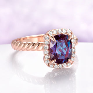 Rose gold ring with a purple gemstone and diamond accents on a light purple background
