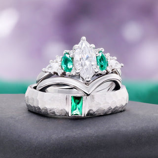 Emerie Diamond & Emerald Couple Ring by Aquamarise, a marquise diamond ring with emerald accents beside a hammered emerald wedding band.