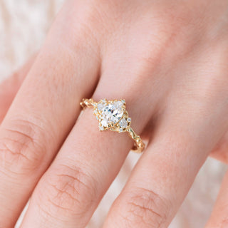 Yellow gold engagement ring with oval cut diamond center stone and diamond accents on hand over a light background 
