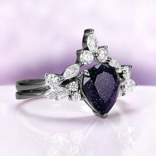 Evelyn Starry Night Ring Set in Black Ruthenium by Aquamarise, featuring a pear-shaped blue sandstone with sparkling accents on black ruthenium sterling silver bands.