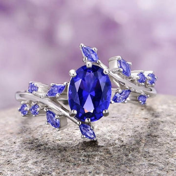 Lab-Grown Oval Cut Cornflower Sapphire Leaf Engagement Ring in 14K White Gold featuring a deep blue oval sapphire and delicate leaf-shaped accents by Aquamarise Gold.