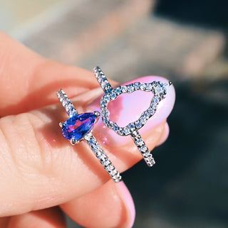 The two Fairest rings held apart on the fingertips, pear solitaire and open halo band side by side
