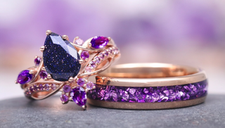 Two purple gemstone rings on a gray surface with a blurred purple background