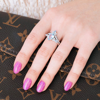 White gold engagement ring set with teardrop cut natural aquamarine center stone and accents on hand over a dark background 