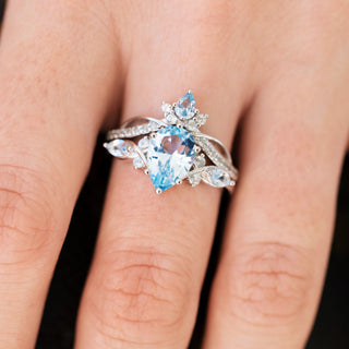 White gold engagement ring set with teardrop cut natural aquamarine center stone and accents on hand over a dark background 