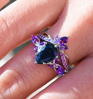 Ring with purple and blue gemstones on a finger