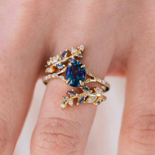 Yellow gold ring with oval cut lab grown alexandrite center stone and diamond accents on hand over a light background