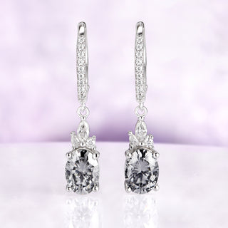 Gray Moissanite Earrings Oval Moissanite Drop Earrings over a light purple background