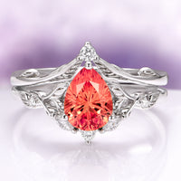 Fireworks Cut Padparadscha Sapphire Engagement Ring Set in 14K White Gold by Aquamarise Gold featuring a pear-shaped fiery padparadscha sapphire centerpiece with detailed leaf-inspired white gold band and diamond accents, part of Solid Gold Engagement Rings and September Birthstone Jewelry collections.
