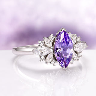 Adeline Marquise Cut Tanzanite Ring in Sterling Silver by Aquamarise, featuring a marquise violet tanzanite surrounded by pear and round white stones on a polished silver band.