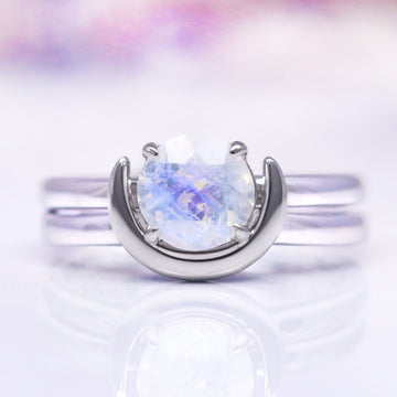 A sterling silver ring with a crescent moon design featuring a moonstone, presented against a white background.