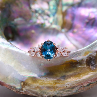 Lily London Blue Topaz Ring in 14K Rose Gold Vermeil by Aquamarise resting inside an iridescent abalone shell, oval topaz with marquise leaf accents
