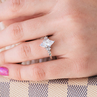 White gold ring with marquise cut diamond center stone and accents on hand over light background 