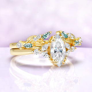 Gold ring with diamonds and green gemstones on a light purple background