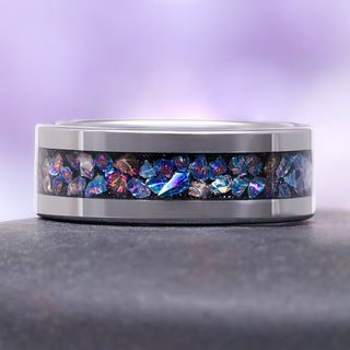 Ring with colorful gemstones on a gray surface and purple background