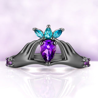 Claddagh engagement ring on its own, sculpted hands holding a 6 x 8 mm pear amethyst under a crown of three simulated Paraiba tourmaline marquises