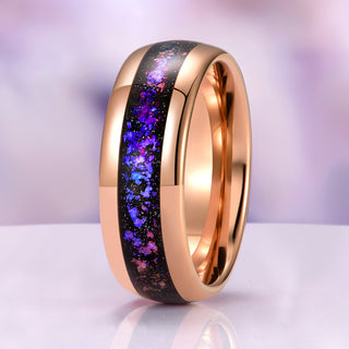 Rose gold ring with purple and black inlay on a reflective surface with a blurred background