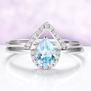 Silver ring with a blue teardrop gemstone on a light purple background