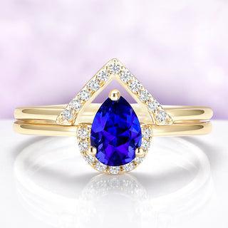Gold ring with a blue gemstone and diamond accents on a light purple background