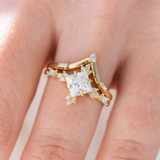 Yellow gold engagement ring set with princess cut diamond center stone and accents on hand over a light background 
