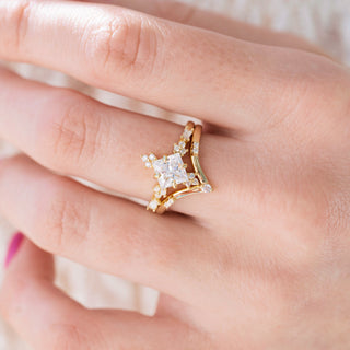 Yellow gold engagement ring set with princess cut diamond center stone and accents on hand over a light background 