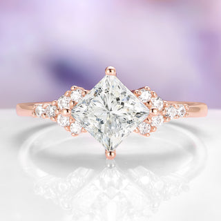 Rose gold ring with a large diamond and smaller diamonds on a soft focus background