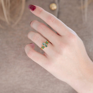 Yellow gold Celtic green moss agate engagement ring with emerald accent stones displayed in hand against warm brown backdrop