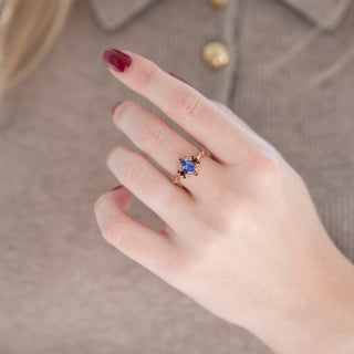 Rose gold oval-shaped alexandrite engagement ring with black onyx accent stones displayed in hand against warm brown backdrop