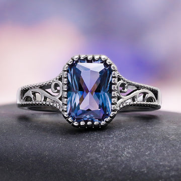Radiant Cut Alexandrite Engagement Ring in Black Ruthenium by Aquamarise, featuring a vintage-inspired band with intricate scrollwork and a radiant-cut purple-hued alexandrite centerpiece.