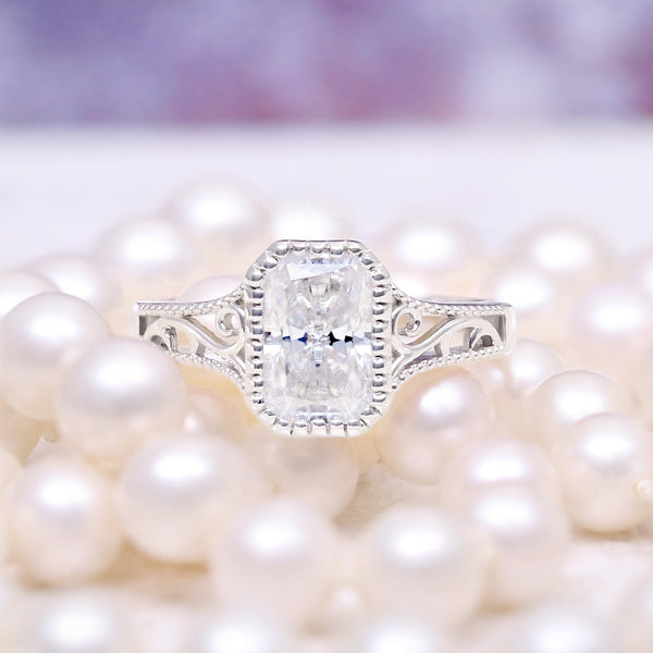 Lab Grown Diamond Engagement Ring in 14K White Gold (IGI Certified) by Aquamarise Gold, featuring an intricate filigree band surrounding a radiant cut diamond on a soft pearl background.
