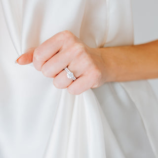 Round diamond ring and band on a hand against a neutral background 