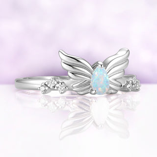 Angled view of the silver Selene wing ring, showing the feather detail on the wings and the blue and green flashes in the white opal