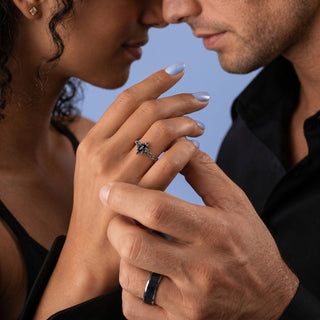Couple dressed in black holding hands while wearing the Shadow Queen Black Onyx Couples Ring Set by Aquamarise, her lotus onyx ring and his black onyx tungsten band