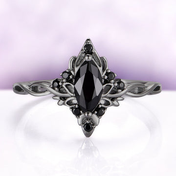Elaborate ring with a black gemstone on a light purple background