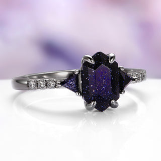 Ring with a purple gemstone and silver accents on a white surface with a blurred purple background