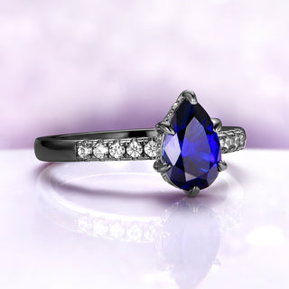 Art Deco Pear Blue Sapphire Ring Set in Black Ruthenium by Aquamarise, featuring a pear-shaped blue sapphire and diamond accents on a sleek black ruthenium band.