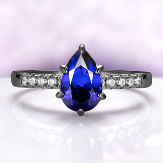 Art Deco Pear Blue Sapphire Ring Set in Black Ruthenium by Aquamarise, showcasing a pear-shaped blue sapphire with diamond accents on a sleek black ruthenium band.