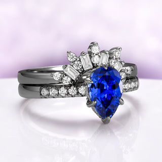 Art Deco Pear Blue Sapphire Ring Set in Black Ruthenium by Aquamarise, featuring a pear-shaped blue sapphire with baguette and round diamond accents on black ruthenium bands.